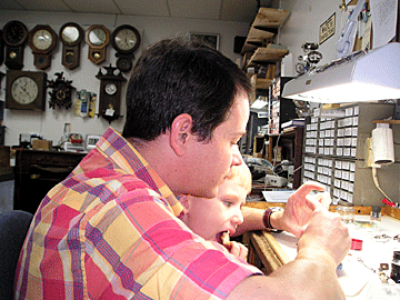 Michael Bowers works on a watch while his nephew looks on.