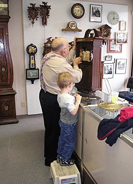 Thomas Bowers works on a clock while his grandson watches.