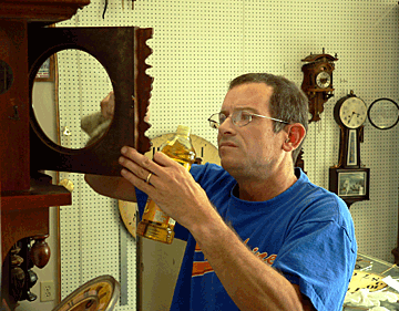 Tim Bowers polishes a clock case.